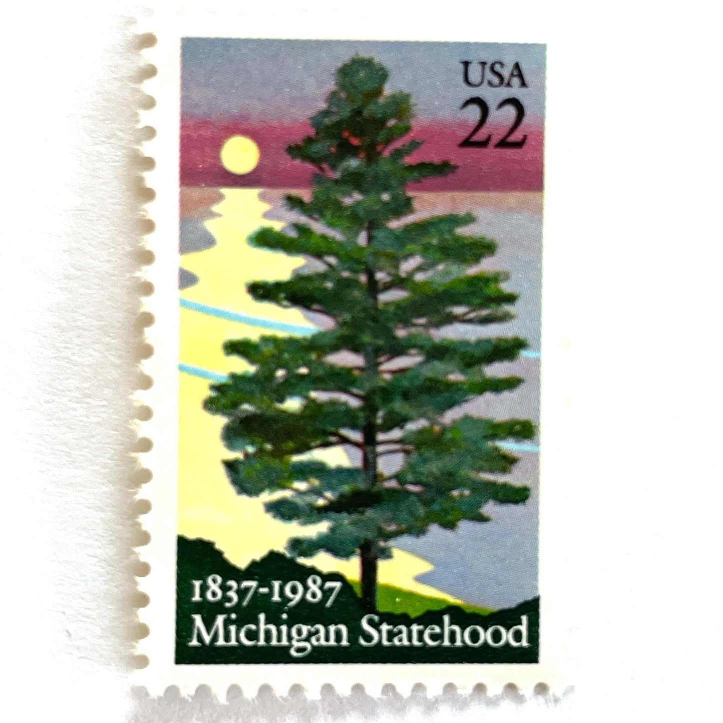 Image of Michigan Statehood postage stamps from 1987, featuring a white pine tree before a sunrise over Lake Huron on vintage unused 22-cent USPS postage, Scott 2246.