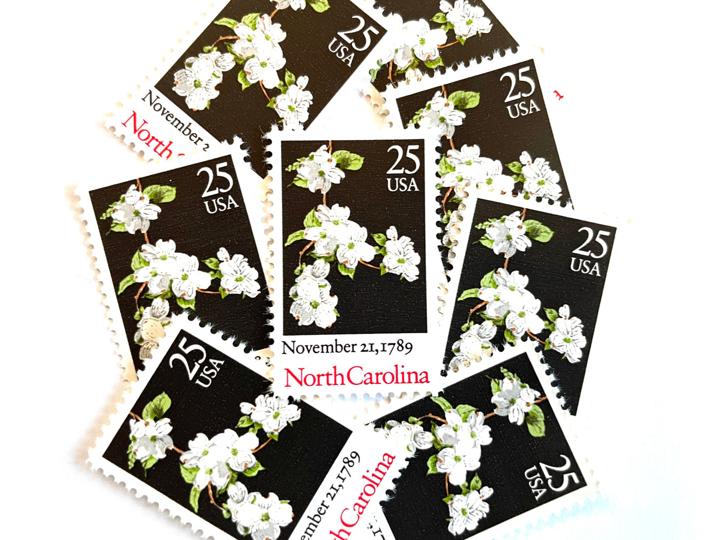 Image of North Carolina Statehood postage stamps from the 1989 Bicentenary Statehood series, featuring white dogwood flowers on a black background on vintage unused 25-cent USPS postage, Scott 2347.