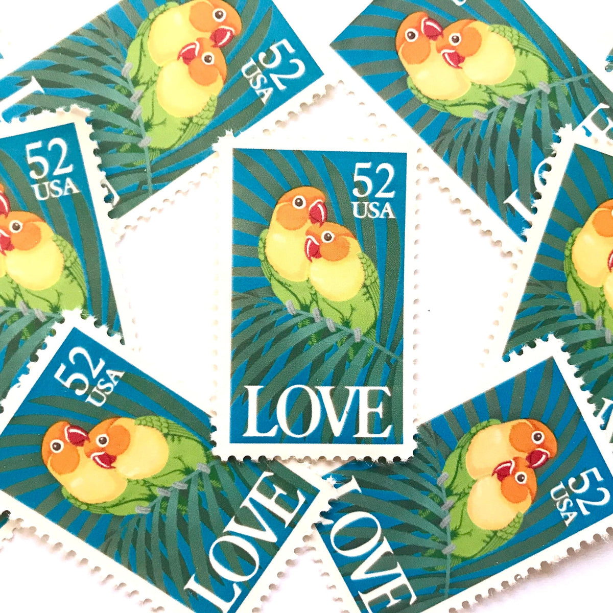 Love Birds postage stamps from 1991 featuring two colorful Fischer’s lovebirds cuddling on a palm frond on vintage unused 52-cent USPS postage, Scott 2537.