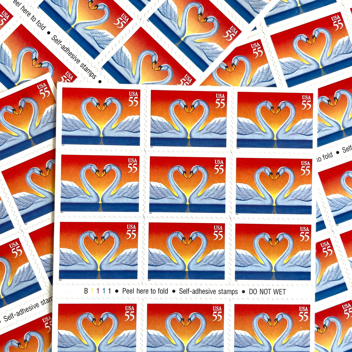 Love Swans postage stamps from 1997 featuring two white swans facing one another with their curved necks forming a heart on vintage unused 55-cent USPS postage, Scott 3124.
