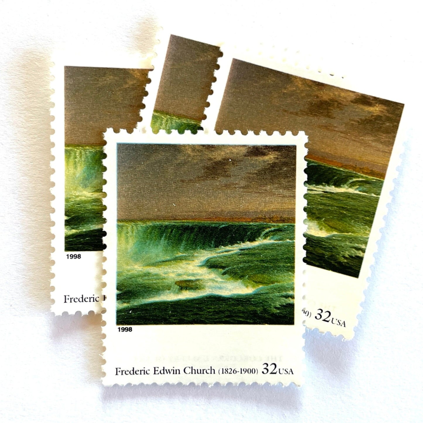 Frederic Edwin Church’s “Niagara” Postage Stamp from the 1998 Four Centuries of American Art Series. This stamp depicts the iconic landscape painting of Niagara Falls. An iconic nature theme, this stamp predominately green postage stamp depicts the waterfall that is shared by the United States and Canada and is a favorite honeymoon destination. These are vintage unused USPS postage stamps with a face value of 32 cents each. Scott number 3236N.