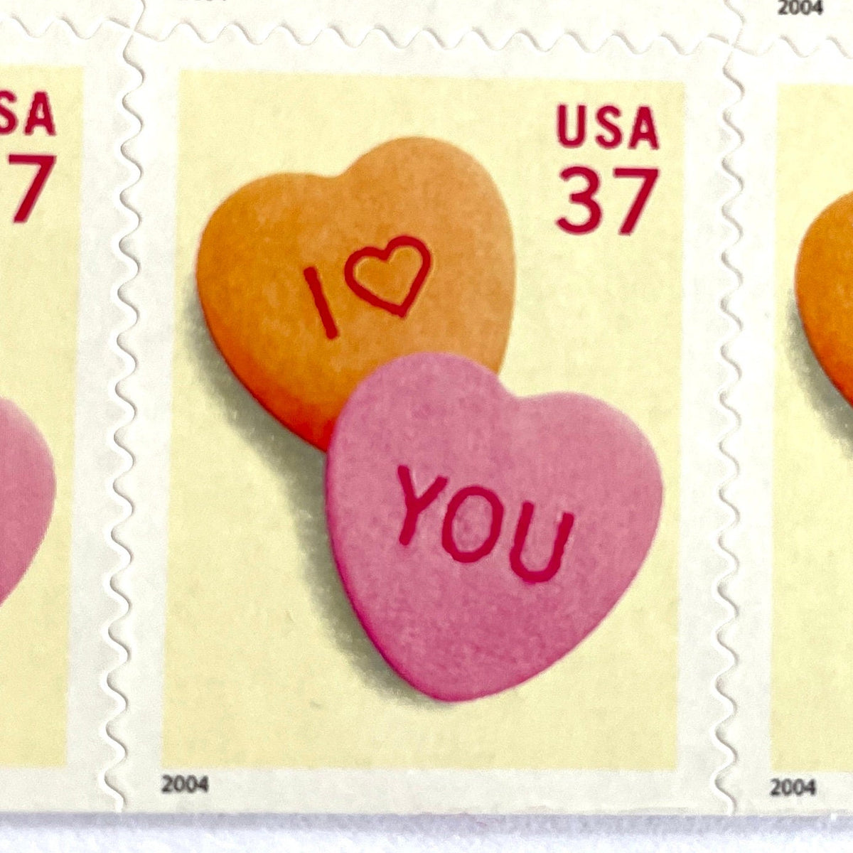 Candy Hearts postage stamps from 2004 featuring pink and yellow conversation hearts spelling I love you on vintage unused 37-cent USPS postage, Scott 3833.