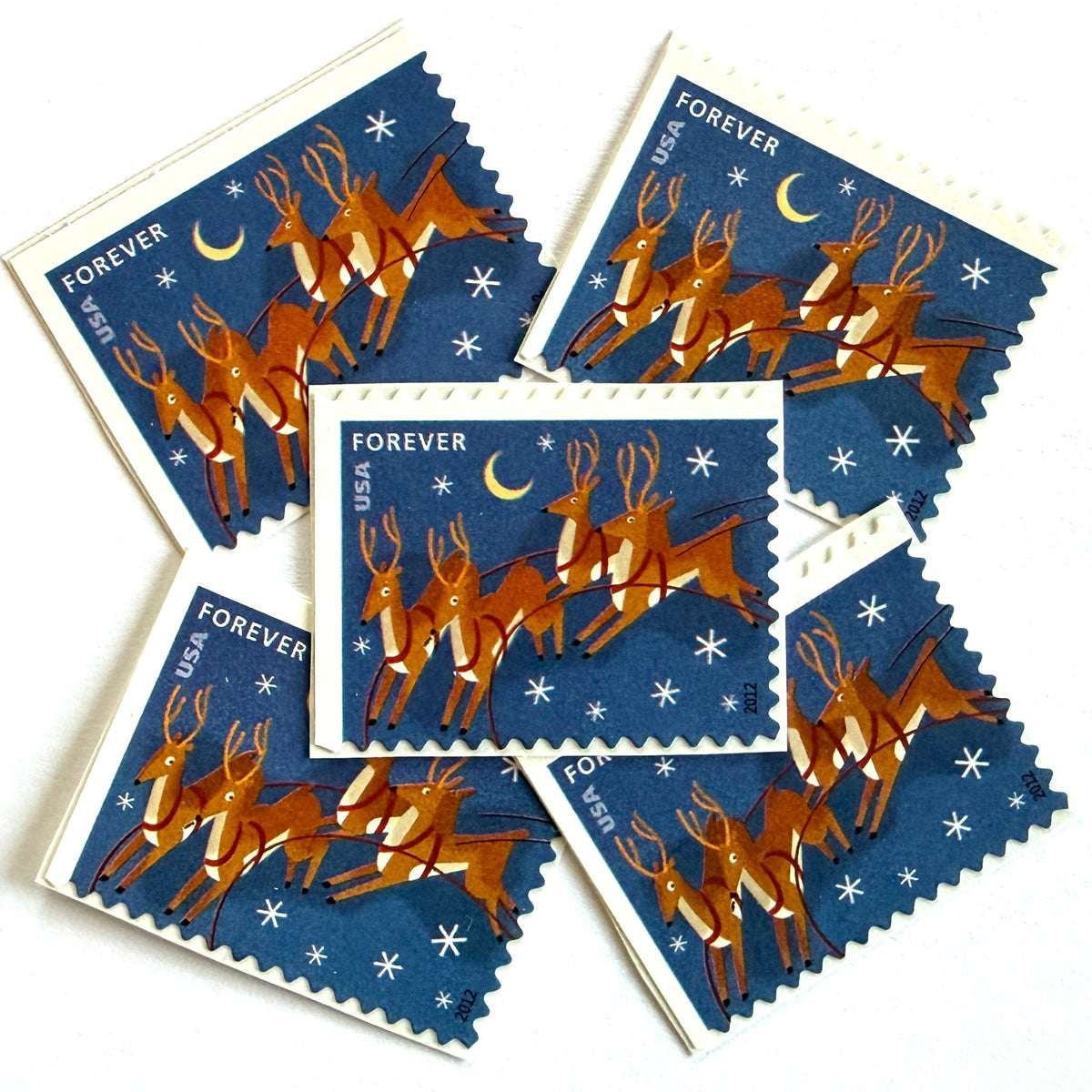 Reindeer in Flight and Moon postage stamps from 2012 featuring flying Christmas reindeer beside a glowing moon in a wintry night sky on unused USPS Forever postage, Scott 4712.