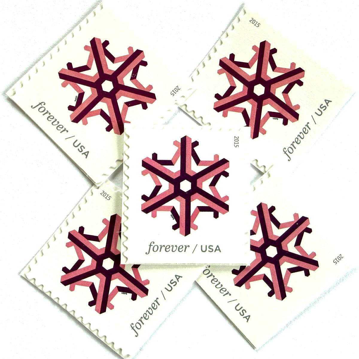 Pink and dark red Geometric Snowflake postage stamps from 2015 featuring a stylized crystalline winter design on unused USPS Forever postage, Scott 5034.