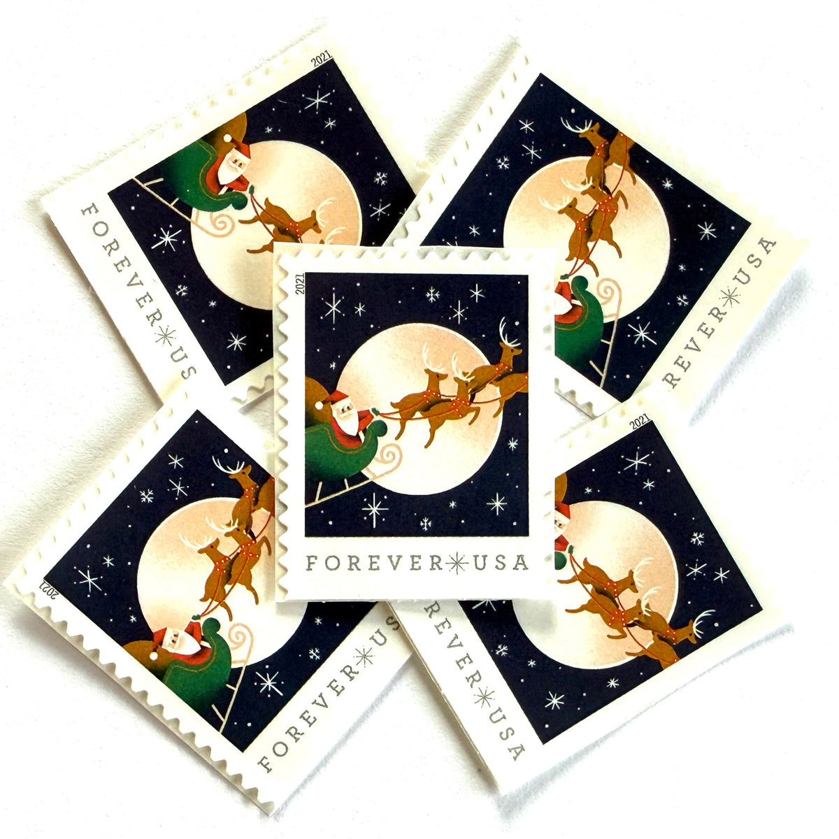 Santa Claus, Sleigh, and Reindeer in Flight postage stamps from 2021 featuring St. Nick and four reindeer flying across a full moon in a dark star-filled sky on unused USPS Forever postage, Scott 5647.