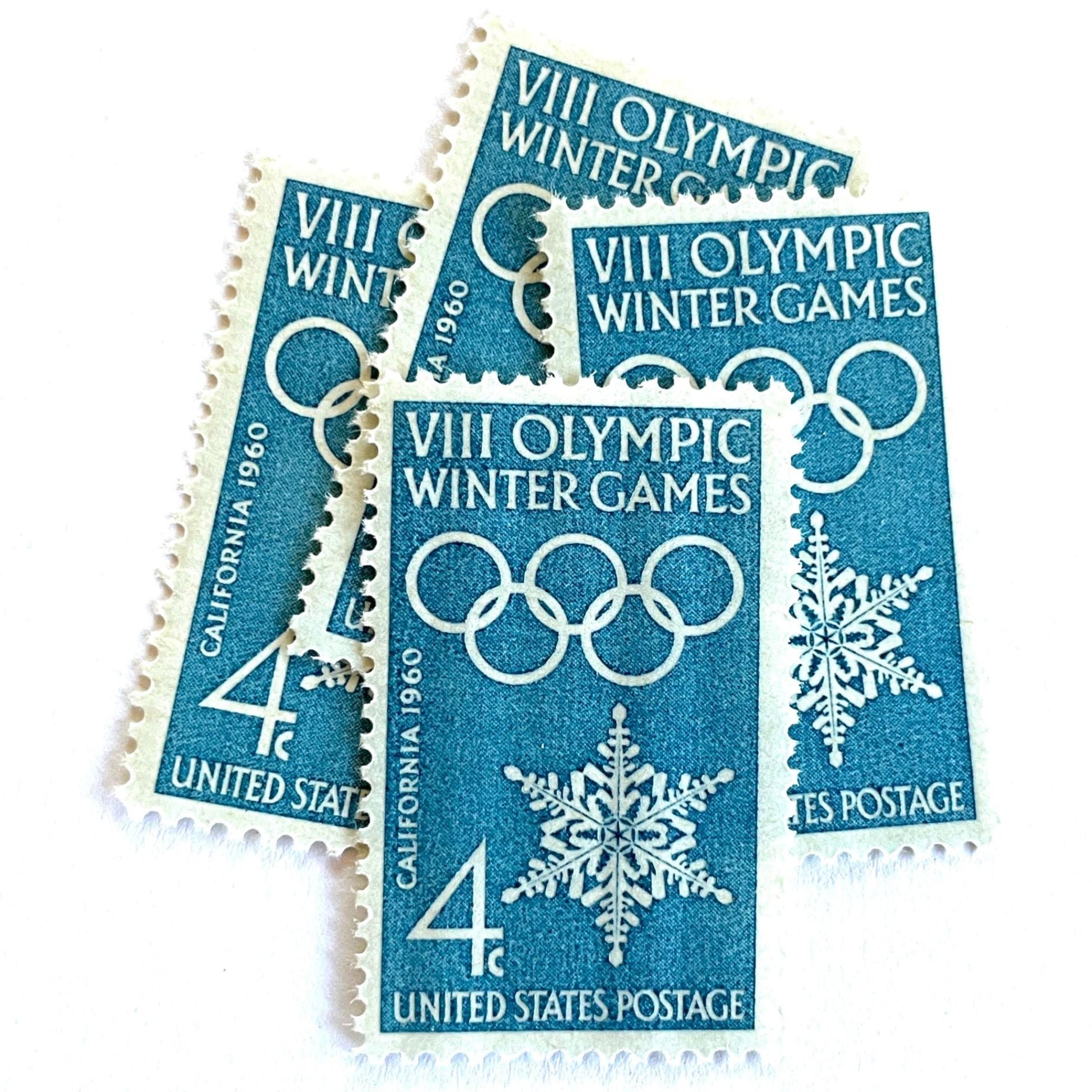 Image of 1960 “VIII Olympic Winter Games” 4-cent mail stamps. Scott #1146. Stamp Themes: 1960 Winter Olympics, Olympic Games, Olympic Rings, Olympiad, Olympic Valley, Lake Tahoe, Squaw Valley, Palisades at Tahoe, Sierra Nevada, California, Snowflake, Winter Postage Stamp. Blue postage stamp.