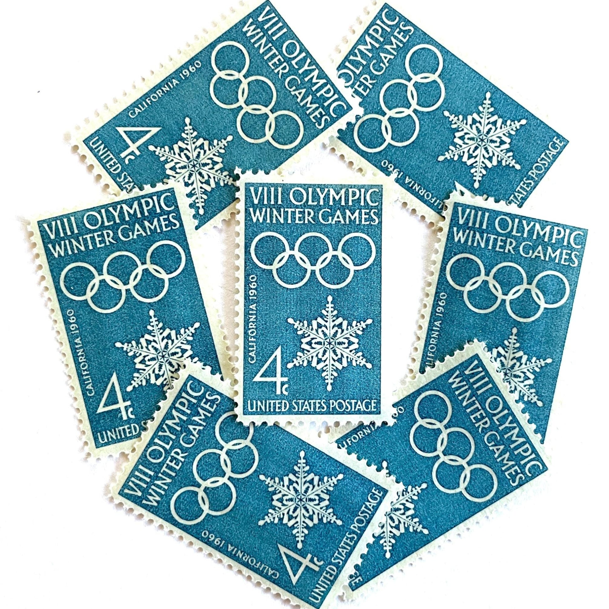 Image of 1960 “VIII Olympic Winter Games” 4-cent mail stamps. Scott #1146. Stamp Themes: 1960 Winter Olympics, Olympic Games, Olympic Rings, Olympiad, Olympic Valley, Lake Tahoe, Squaw Valley, Palisades at Tahoe, Sierra Nevada, California, Snowflake, Winter Postage Stamp. Blue postage stamp.