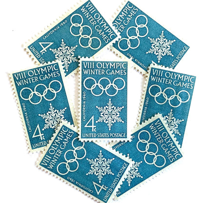 Image of 1960 “VIII Olympic Winter Games” 4-cent mail stamps. Scott #1146. Stamp Themes: 1960 Winter Olympics, Olympic Games, Olympic Rings, Olympiad, Olympic Valley, Lake Tahoe, Squaw Valley, Palisades at Tahoe, Sierra Nevada, California, Snowflake, Winter Postage Stamp. Blue postage stamp.