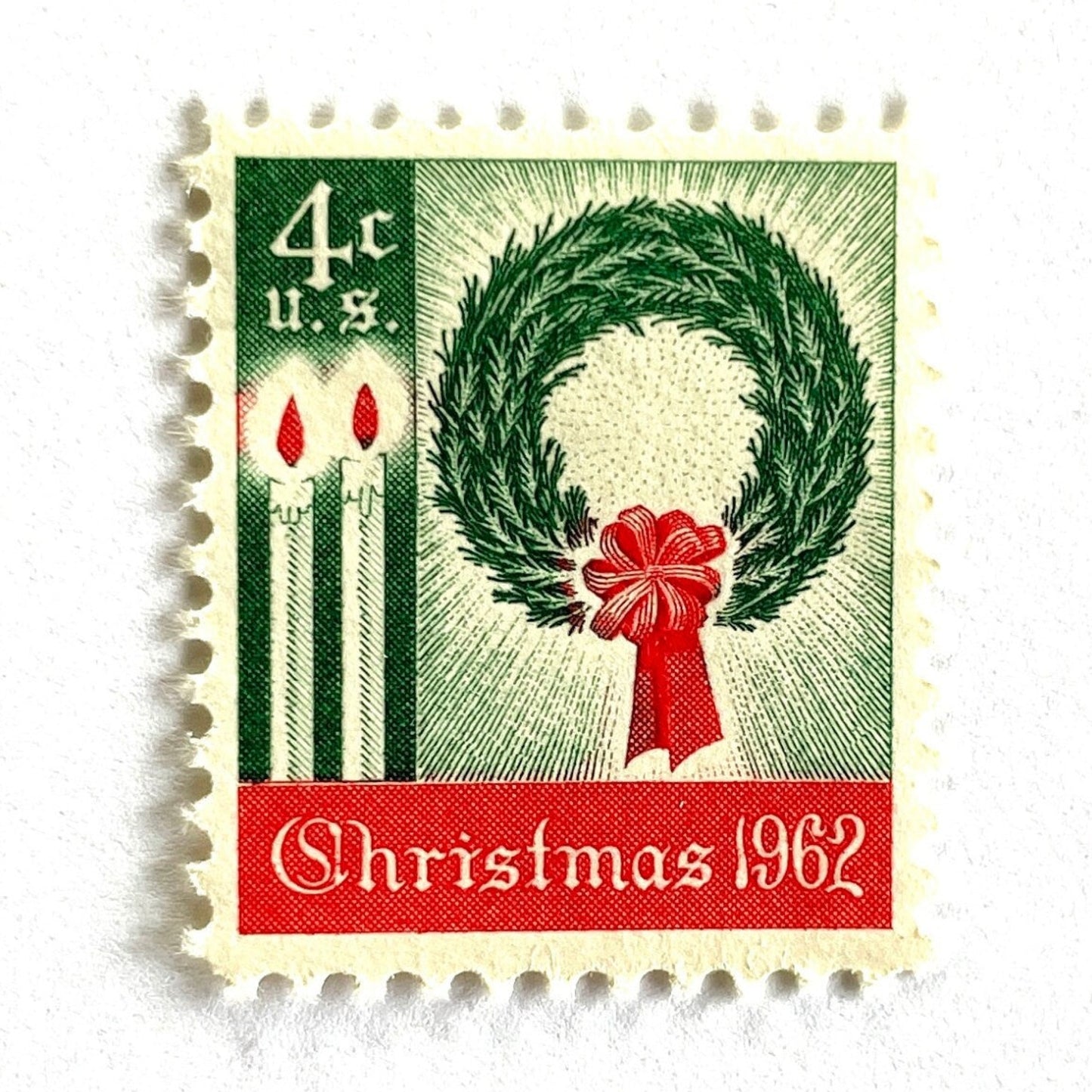 Image of 1962 Contemporary Christmas “Christmas Wreath and Candles” 4-cent stamps. Scott #1205. Stamp Themes: Wreath, Candles, Red Bow, Holidays, First U.S. Christmas Stamp. Green and red postage stamp.