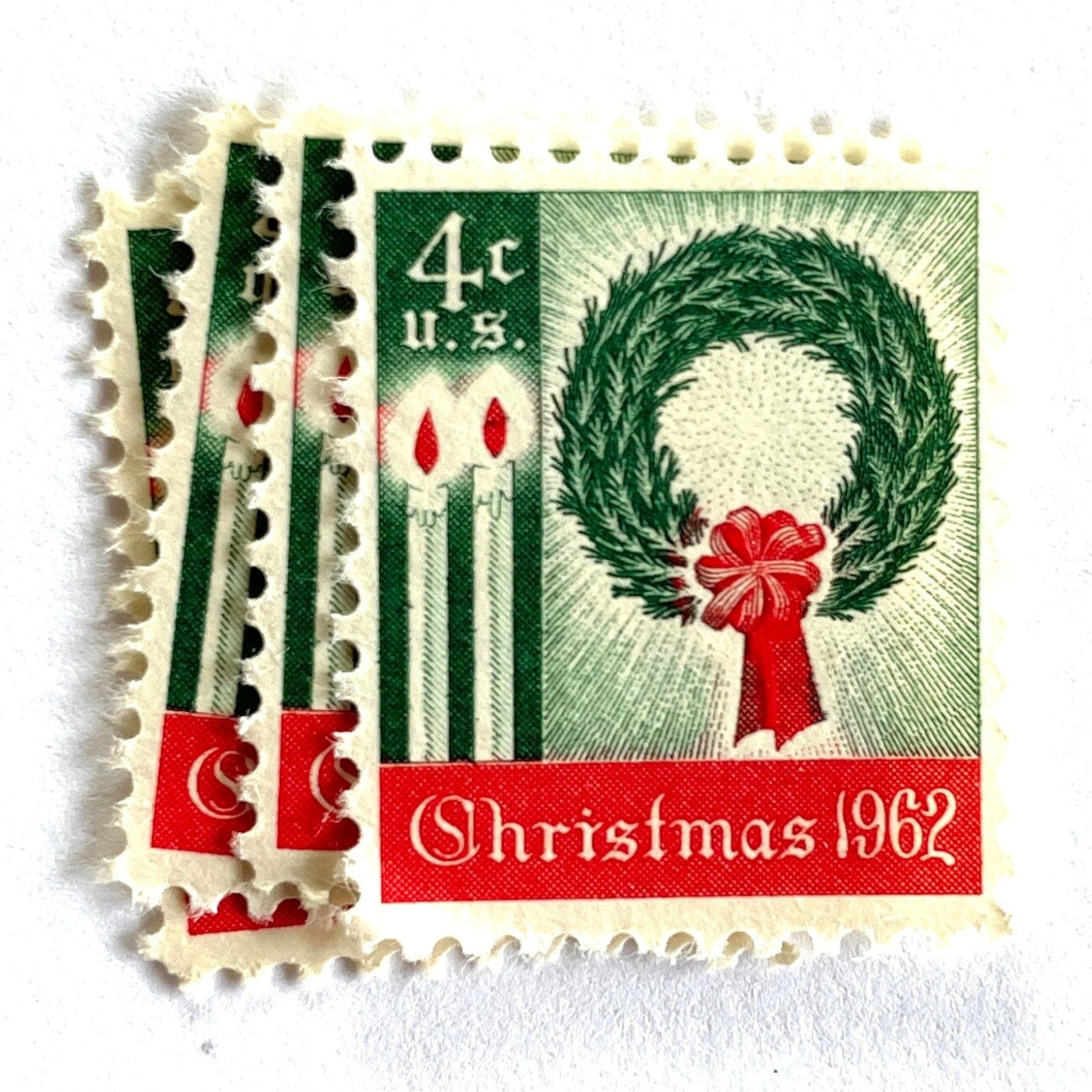 Image of 1962 Contemporary Christmas “Christmas Wreath and Candles” 4-cent stamps. Scott #1205. Stamp Themes: Wreath, Candles, Red Bow, Holidays, First U.S. Christmas Stamp. Green and red postage stamp.