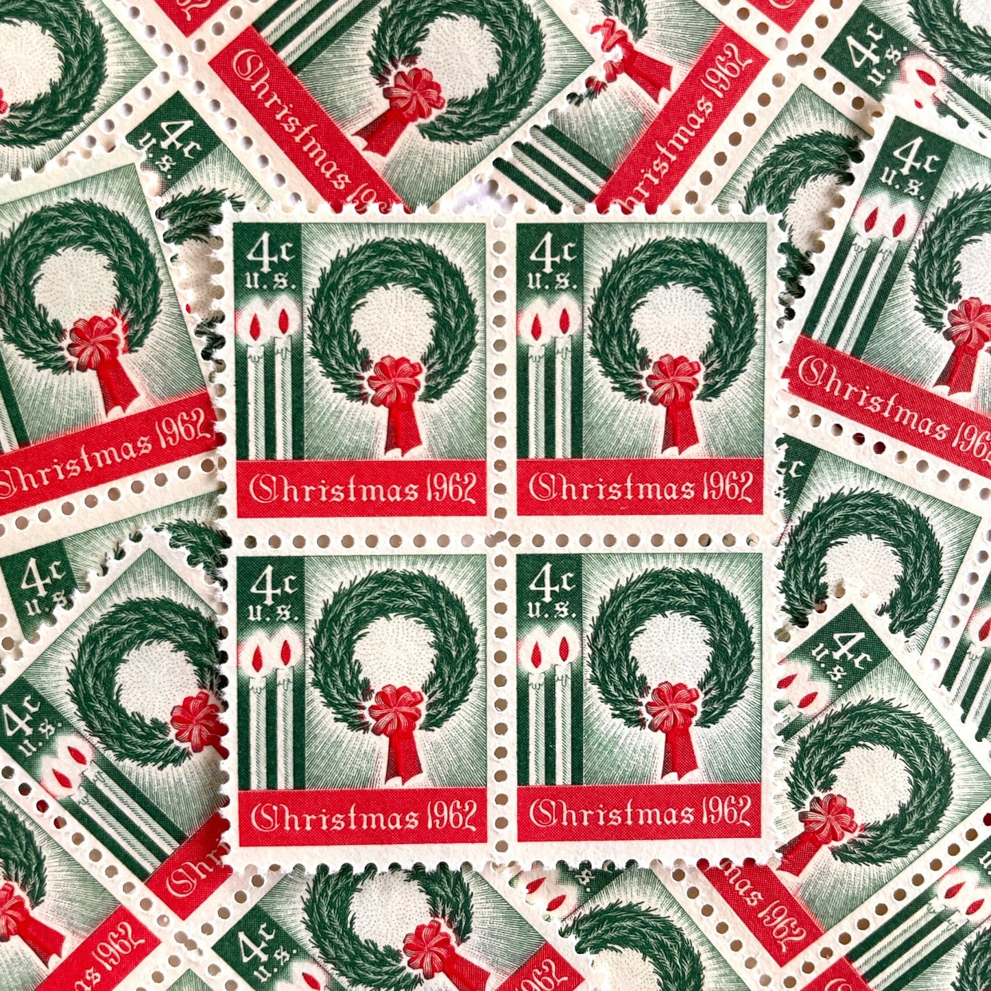 Image of 1962 Contemporary Christmas “Christmas Wreath and Candles” 4-cent stamps. Scott #1205. Stamp Themes: Wreath, Candles, Red Bow, Holidays, First U.S. Christmas Stamp. Green and red postage stamp.