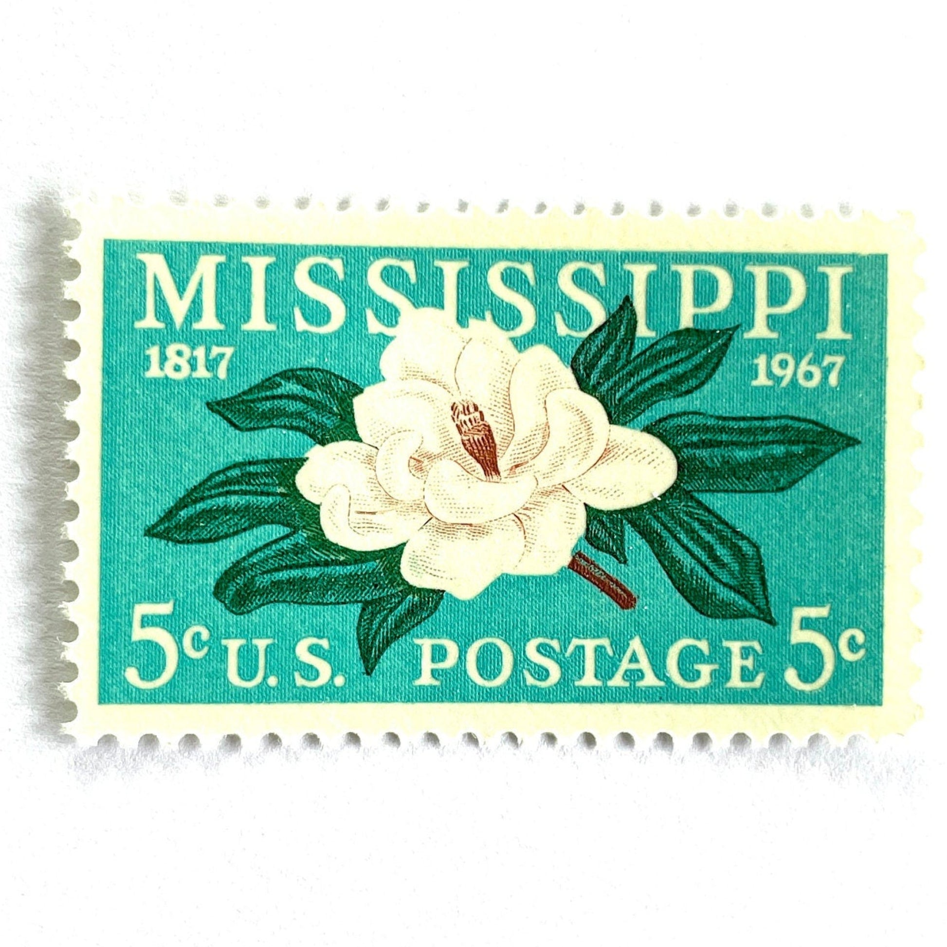 Image of a Mississippi Statehood postage stamp from 1967, featuring a magnolia flower design on vintage unused 5-cent USPS postage, Scott 1337.