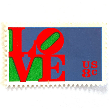 Red LOVE postage stamp from 1973 featuring Robert Indiana’s iconic red, green, and violet blue LOVE design on vintage unused 8-cent USPS postage, Scott 1475.