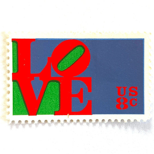 Red LOVE postage stamp from 1973 featuring Robert Indiana’s iconic red, green, and violet blue LOVE design on vintage unused 8-cent USPS postage, Scott 1475.
