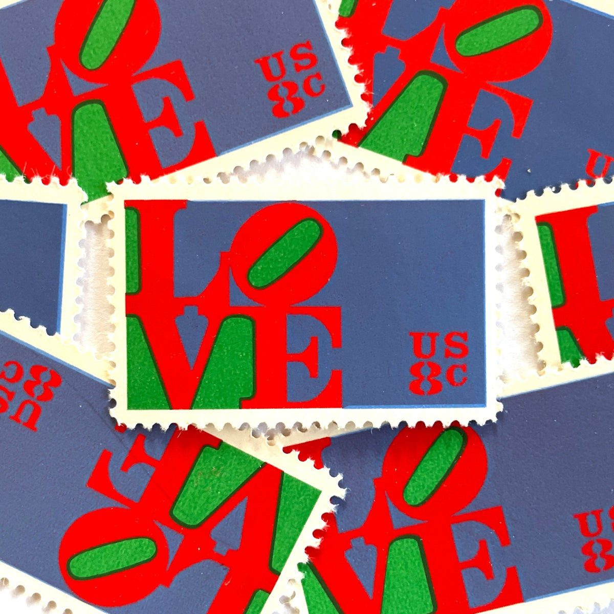 Red LOVE postage stamps from 1973 featuring Robert Indiana’s iconic red, green, and violet blue LOVE design on vintage unused 8-cent USPS postage, Scott 1475.