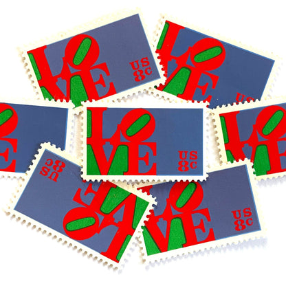 Red LOVE postage stamps from 1973 featuring Robert Indiana’s iconic red, green, and violet blue LOVE design on vintage unused 8-cent USPS postage, Scott 1475.