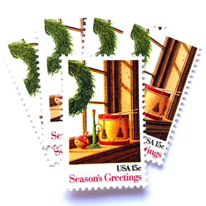 Image of 1980 Contemporary Christmas “Wreath and Toys on Window” 15-cent stamps. Scott #1843. Stamp Themes: Christmas, Holidays, Toys, Musical Instruments, Drum, Horn, Spinning Top. Multicolored postage stamp.