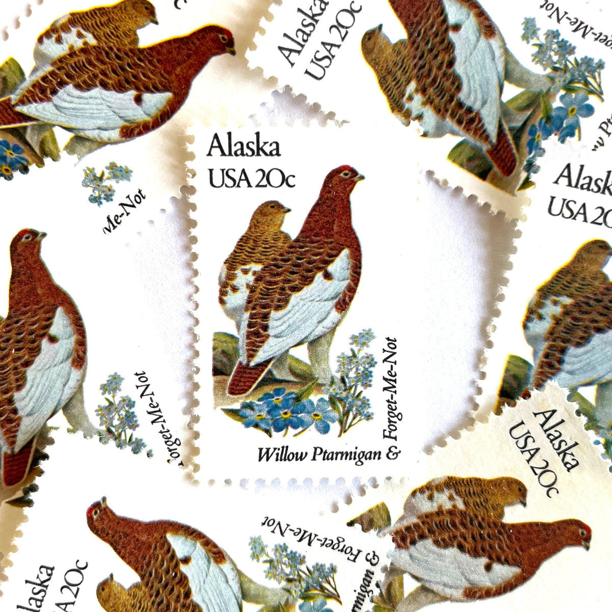 Alaska State Bird and Flower postage stamps from 1982 featuring a Willow Ptarmigan and Forget-Me-Not on vintage unused 20-cent USPS postage, Scott 1954.