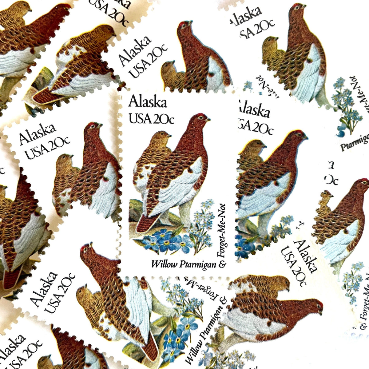 Alaska State Bird and Flower postage stamps from 1982 featuring a Willow Ptarmigan and Forget-Me-Not on vintage unused 20-cent USPS postage, Scott 1954.