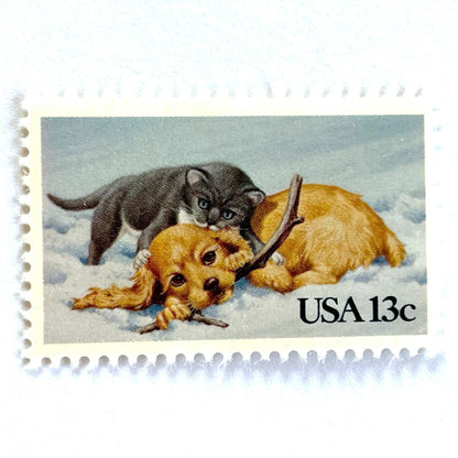 Image of 1982 Christmas Issue “Kitten and Puppy” 13-cent stamps. Scott #2025. Stamp Themes: Pets, Cat, Dog, Humane Society, Play, Snow, Winter. Light Blue postage stamp.