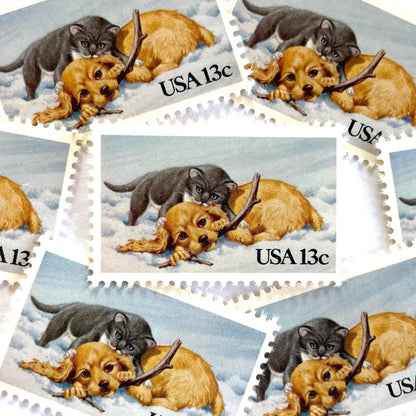 Image of 1982 Christmas Issue “Kitten and Puppy” 13-cent stamps. Scott #2025. Stamp Themes: Pets, Cat, Dog, Humane Society, Play, Snow, Winter. Light Blue postage stamp.