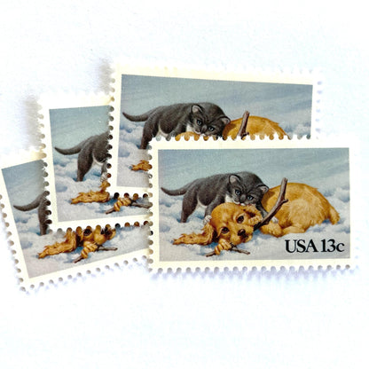 Image of 1982 Christmas Issue “Kitten and Puppy” 13-cent stamps. Scott #2025. Stamp Themes: Pets, Cat, Dog, Humane Society, Play, Snow, Winter. Light Blue postage stamp.