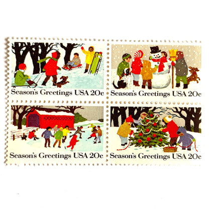 Image of 1982 Contemporary Christmas “Season's Greetings” 20 cent stamps. Scott #2027-30. Stamp Themes: Christmas, Holidays, Winter, Sledding, Ice Skating, Snowman Building, Christmas Tree Decorating, Snow, Cold, Children Playing. Christmas Issue Se-Tenant set of four connected stamps.