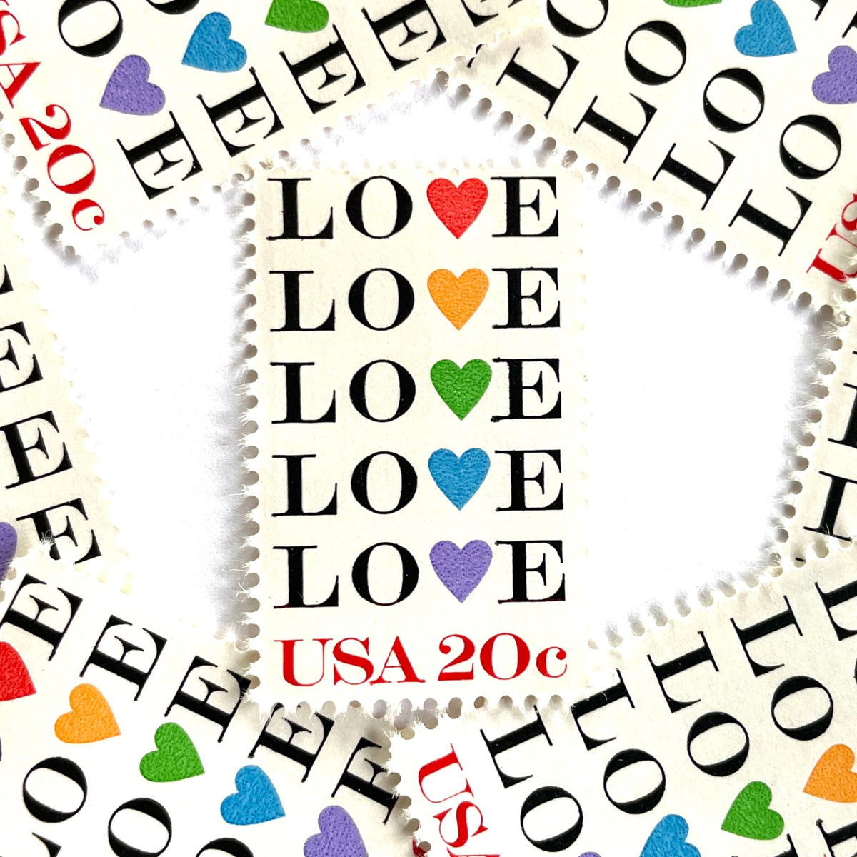 Love with Hearts postage stamps from 1984 featuring repeated LOVE lettering with five different-colored hearts on vintage unused 20-cent USPS postage, Scott 2072.