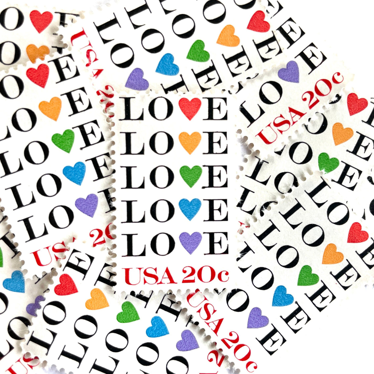 Love with Hearts postage stamps from 1984 featuring repeated LOVE lettering with five different-colored hearts on vintage unused 20-cent USPS postage, Scott 2072.