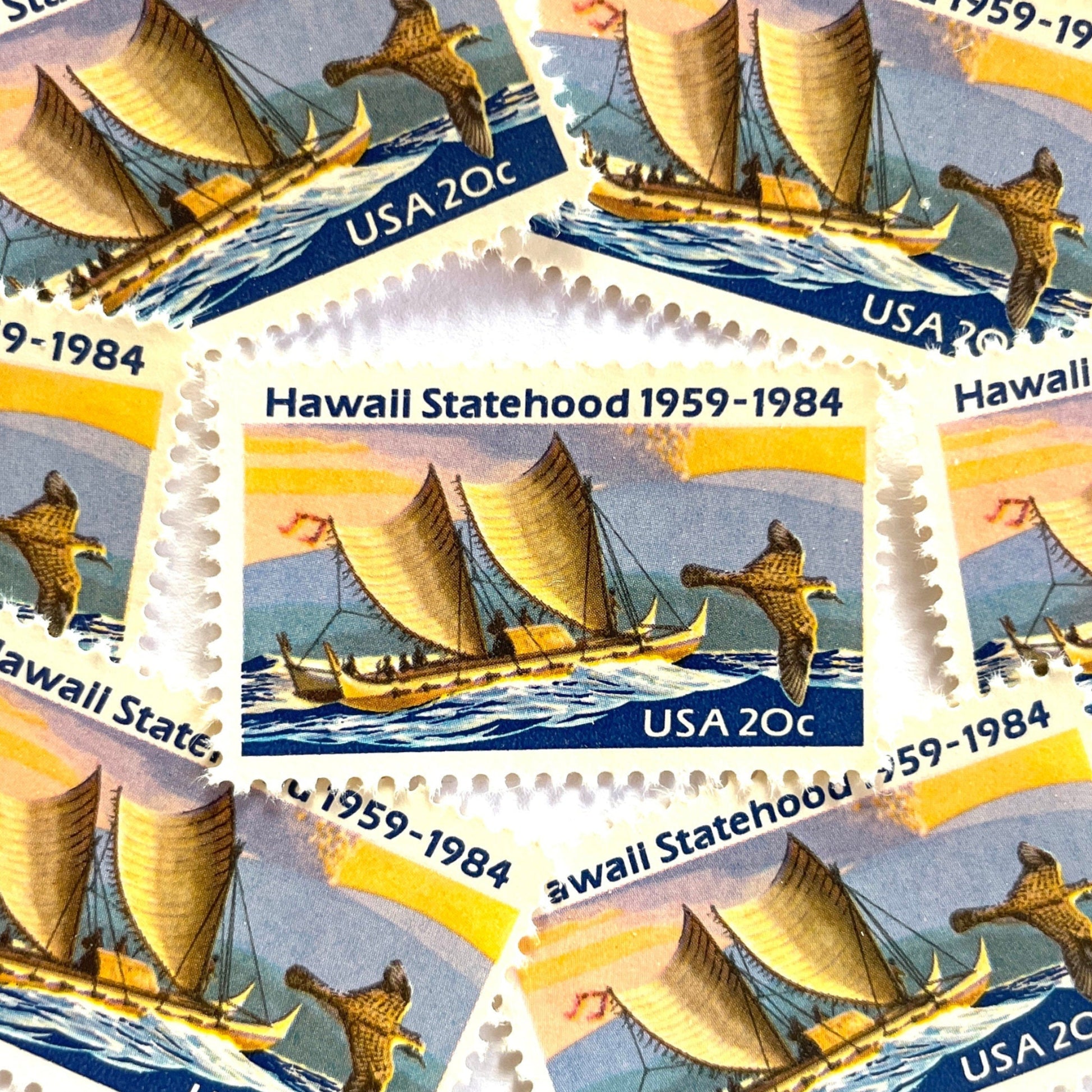 Image of Hawaii Statehood postage stamps from 1984, featuring a Polynesian voyaging canoe on the ocean, a golden plover in flight, and an erupting Mauna Loa volcano on vintage unused 20-cent USPS postage, Scott 2080.