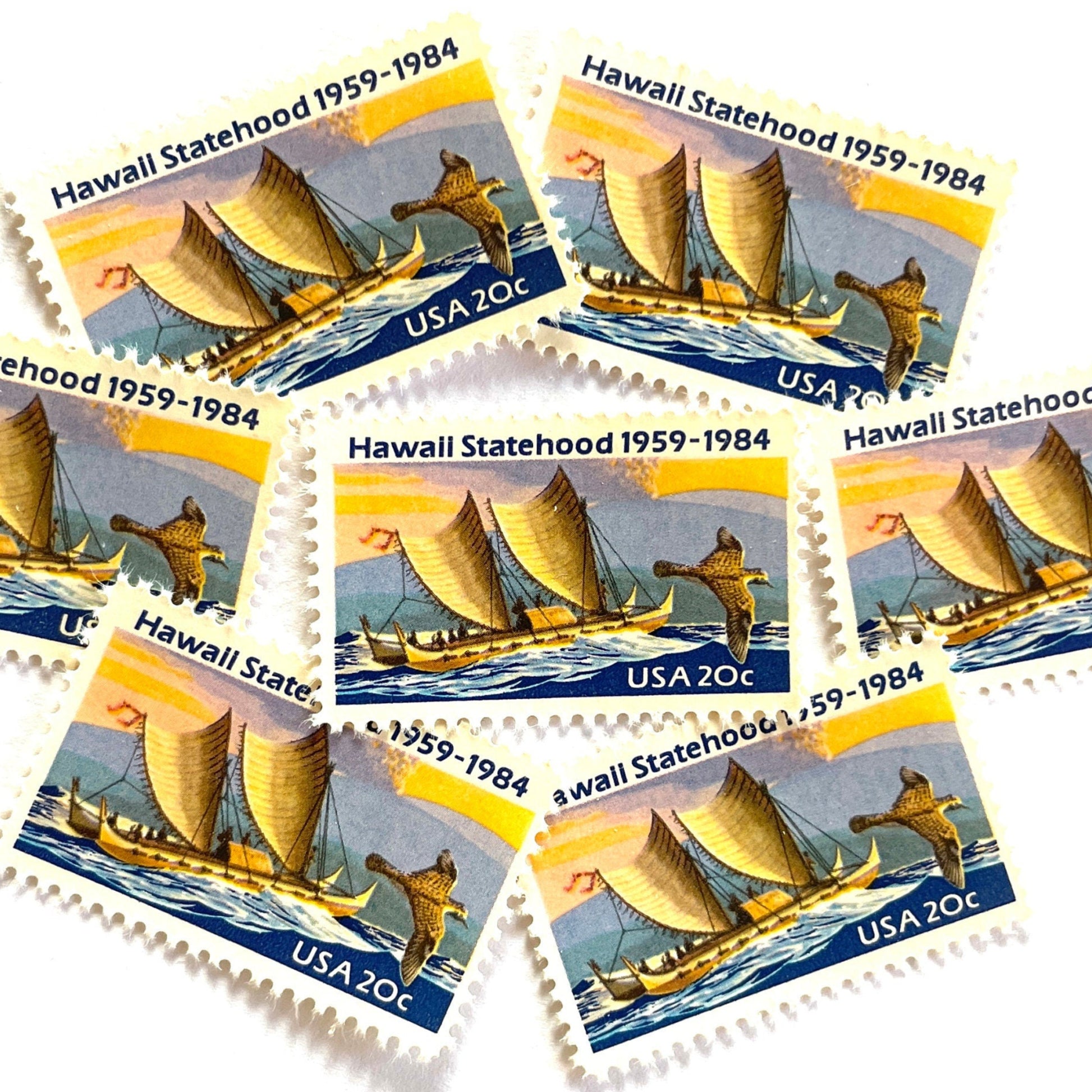 Image of Hawaii Statehood postage stamps from 1984, featuring a Polynesian voyaging canoe on the ocean, a golden plover in flight, and an erupting Mauna Loa volcano on vintage unused 20-cent USPS postage, Scott 2080.