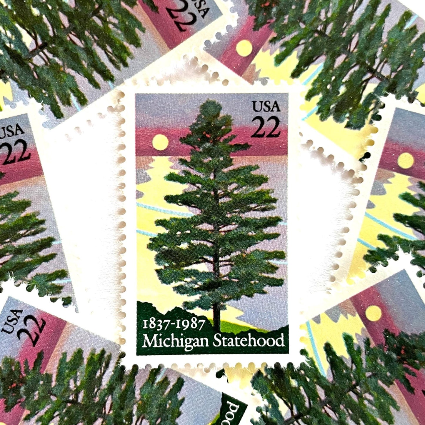 Image of Michigan Statehood postage stamps from 1987, featuring a white pine tree before a sunrise over Lake Huron on vintage unused 22-cent USPS postage, Scott 2246.