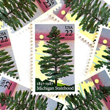 Image of Michigan Statehood postage stamps from 1987, featuring a white pine tree before a sunrise over Lake Huron on vintage unused 22-cent USPS postage, Scott 2246.