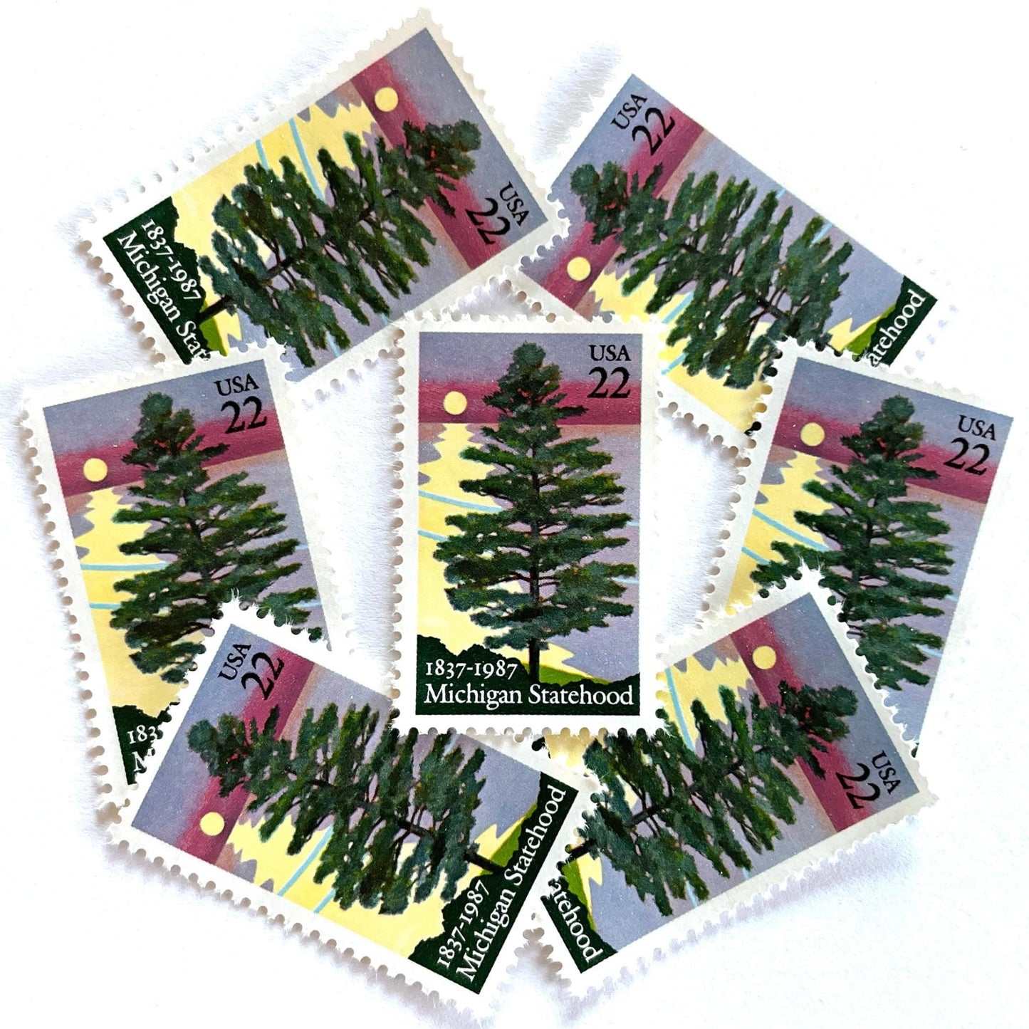 Image of Michigan Statehood postage stamps from 1987, featuring a white pine tree before a sunrise over Lake Huron on vintage unused 22-cent USPS postage, Scott 2246.