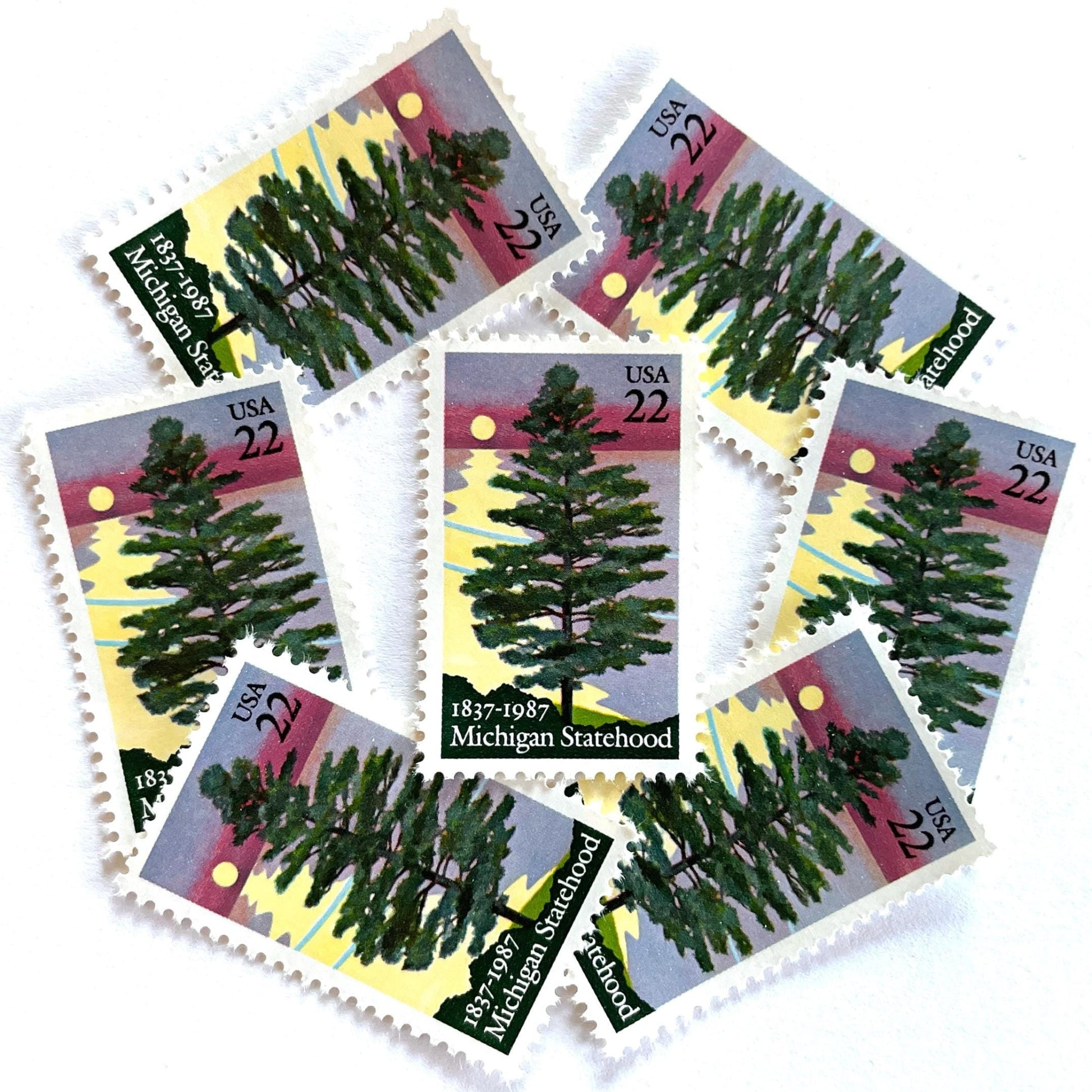 Image of Michigan Statehood postage stamps from 1987, featuring a white pine tree before a sunrise over Lake Huron on vintage unused 22-cent USPS postage, Scott 2246.