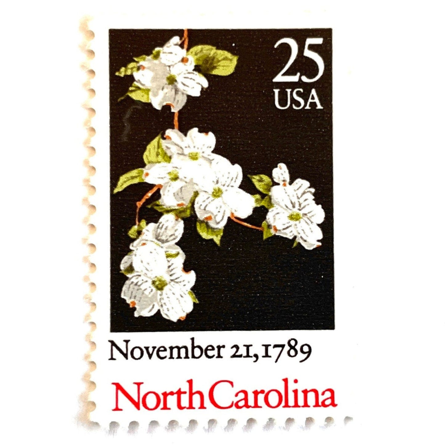 Image of North Carolina Statehood postage stamps from the 1989 Bicentenary Statehood series, featuring white dogwood flowers on a black background on vintage unused 25-cent USPS postage, Scott 2347.