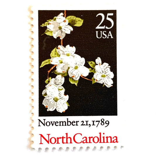 Image of North Carolina Statehood postage stamps from the 1989 Bicentenary Statehood series, featuring white dogwood flowers on a black background on vintage unused 25-cent USPS postage, Scott 2347.