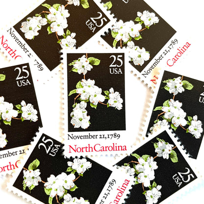 Image of North Carolina Statehood postage stamps from the 1989 Bicentenary Statehood series, featuring white dogwood flowers on a black background on vintage unused 25-cent USPS postage, Scott 2347.