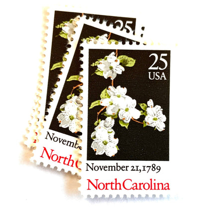 Image of North Carolina Statehood postage stamps from the 1989 Bicentenary Statehood series, featuring white dogwood flowers on a black background on vintage unused 25-cent USPS postage, Scott 2347.