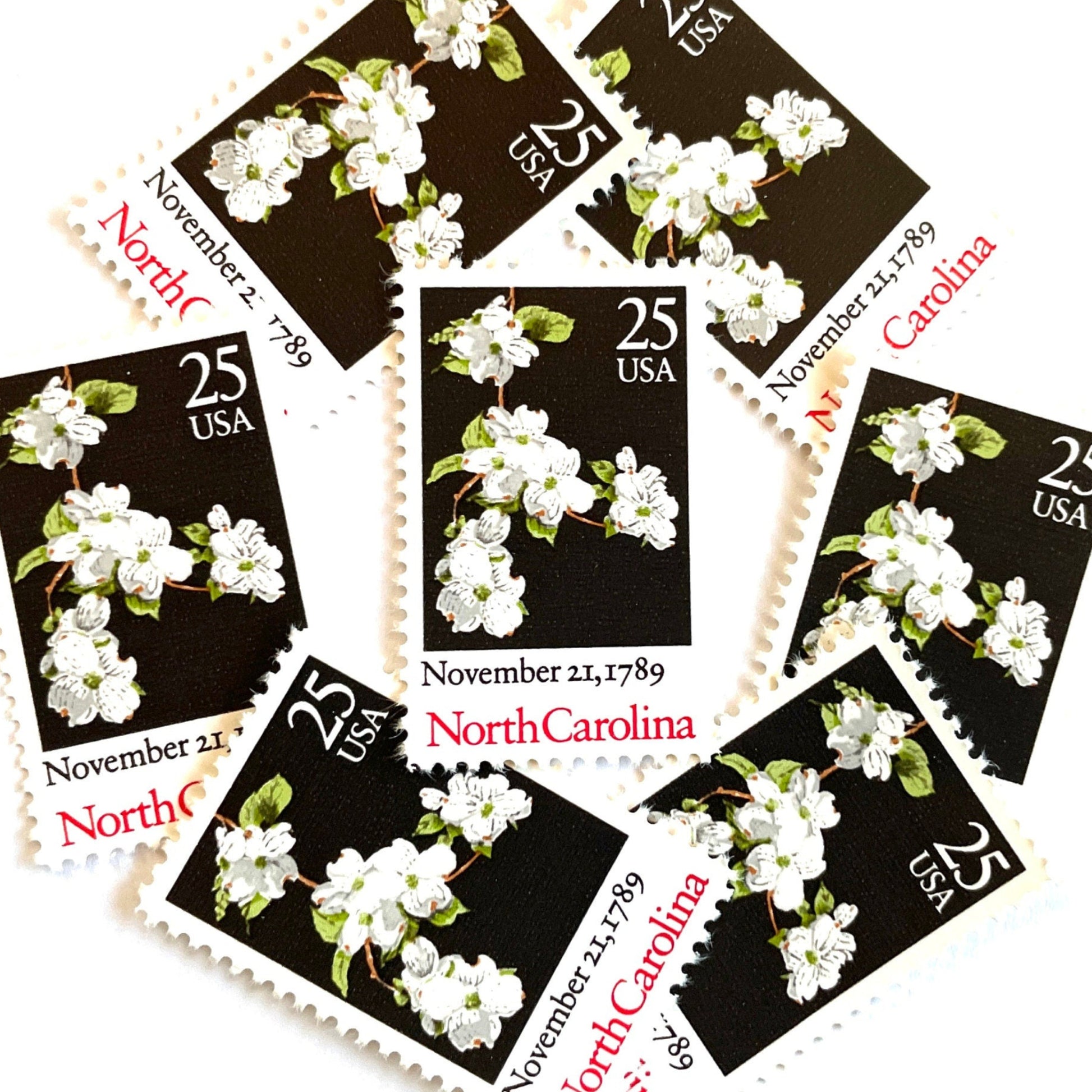 Image of North Carolina Statehood postage stamps from the 1989 Bicentenary Statehood series, featuring white dogwood flowers on a black background on vintage unused 25-cent USPS postage, Scott 2347.