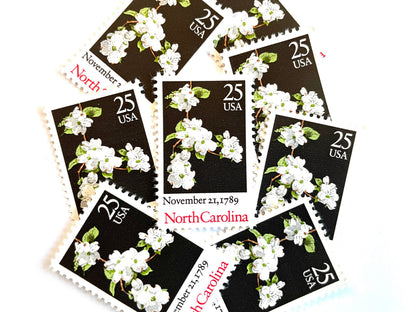 Image of North Carolina Statehood postage stamps from the 1989 Bicentenary Statehood series, featuring white dogwood flowers on a black background on vintage unused 25-cent USPS postage, Scott 2347.