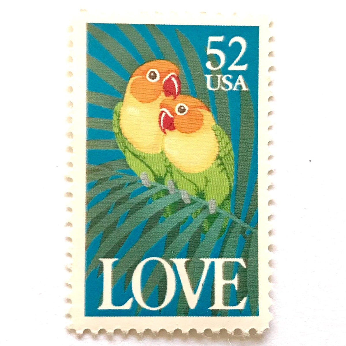 Love Birds postage stamp from 1991 featuring two colorful Fischer’s lovebirds cuddling on a palm frond on vintage unused 52-cent USPS postage, Scott 2537.