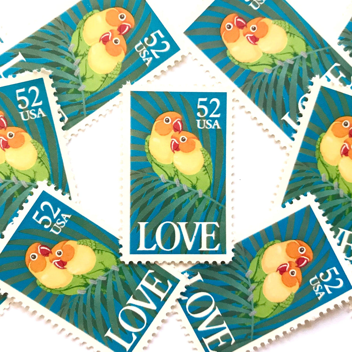 Love Birds postage stamps from 1991 featuring two colorful Fischer’s lovebirds cuddling on a palm frond on vintage unused 52-cent USPS postage, Scott 2537.