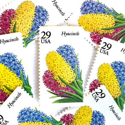 Image of Hyacinth postage stamps from the 1993 Spring Garden Flowers series, featuring purple hyacinth blooms with green foliage on vintage unused 29-cent USPS postage, Scott 2760. Colombian Flag Colors: Yellow, Blue, Red
