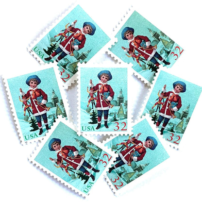 Image of 32-cent Contemporary Christmas 1995 Santa and Children “Child with Jumping Jack” USPS postage stamps featuring a young boy with blond, curly hair and a blue cap, dressed in a festive red coat with white fur trim, holding a traditional wooden jumping jack toy in one hand and a golden trumpet in the other. Scott #3005. Stamp themes: Christmas, holidays, winter, Santa Claus, toys, gifts, winter wedding, winter save-the-date. Green and red postage stamp.