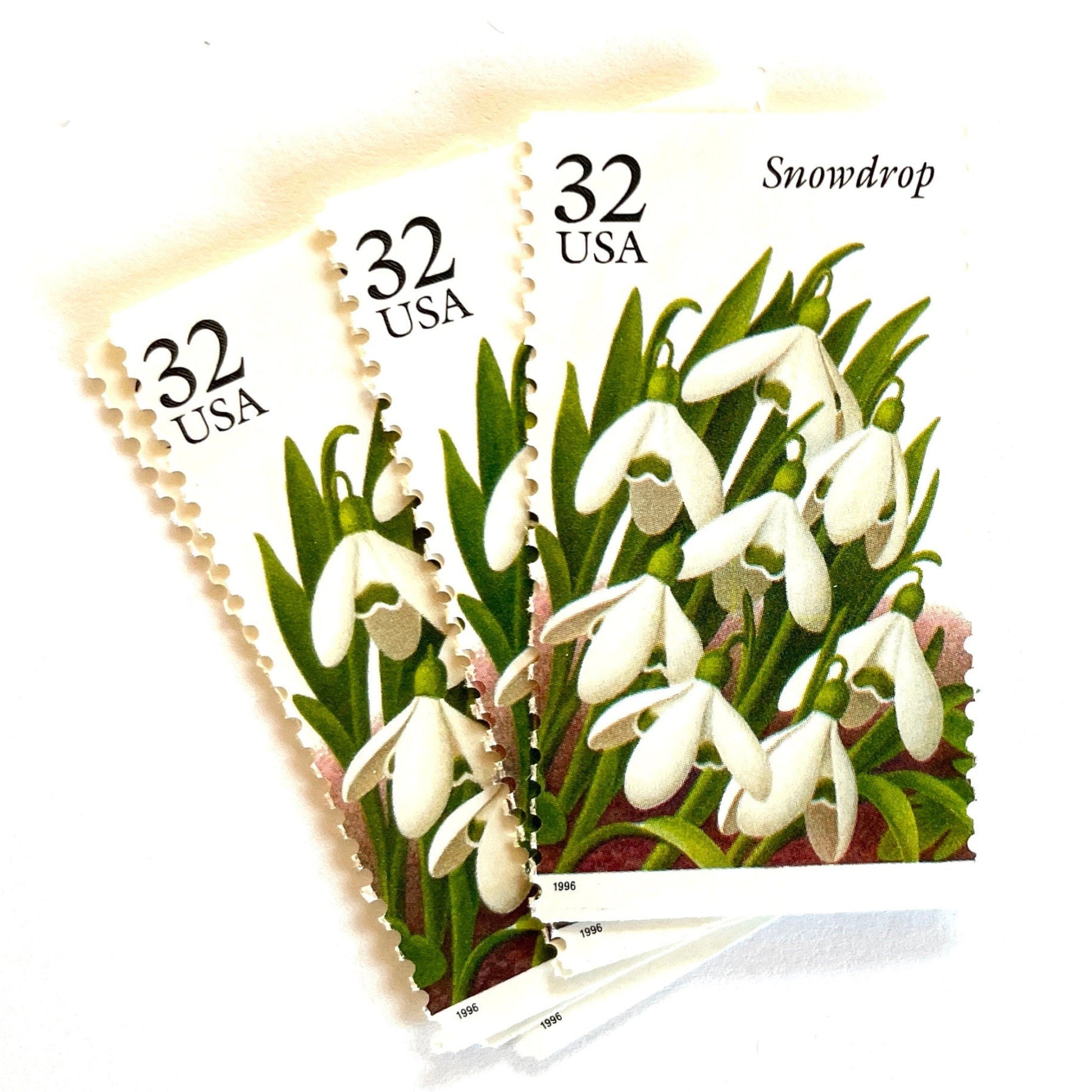 Image of Snowdrop postage stamps from the Winter Garden Flowers series, featuring white winter-blooming flowers with green leaves and brown garden soil on vintage 1996 unused 32-cent USPS postage, Scott 3028.
