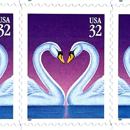Love Swans postage stamp from 1997 featuring two white swans facing one another with their curved necks forming a heart against a purple background on vintage unused 32-cent USPS postage, Scott 3123.