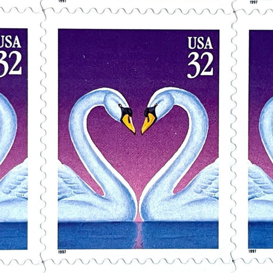 Love Swans postage stamp from 1997 featuring two white swans facing one another with their curved necks forming a heart against a purple background on vintage unused 32-cent USPS postage, Scott 3123.