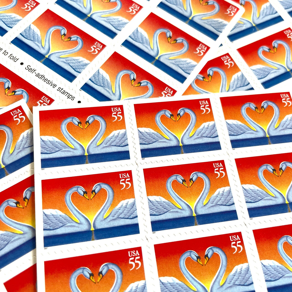 Love Swans postage stamps from 1997 featuring two white swans facing one another with their curved necks forming a heart on vintage unused 55-cent USPS postage, Scott 3124.