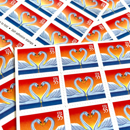 Love Swans postage stamps from 1997 featuring two white swans facing one another with their curved necks forming a heart on vintage unused 55-cent USPS postage, Scott 3124.